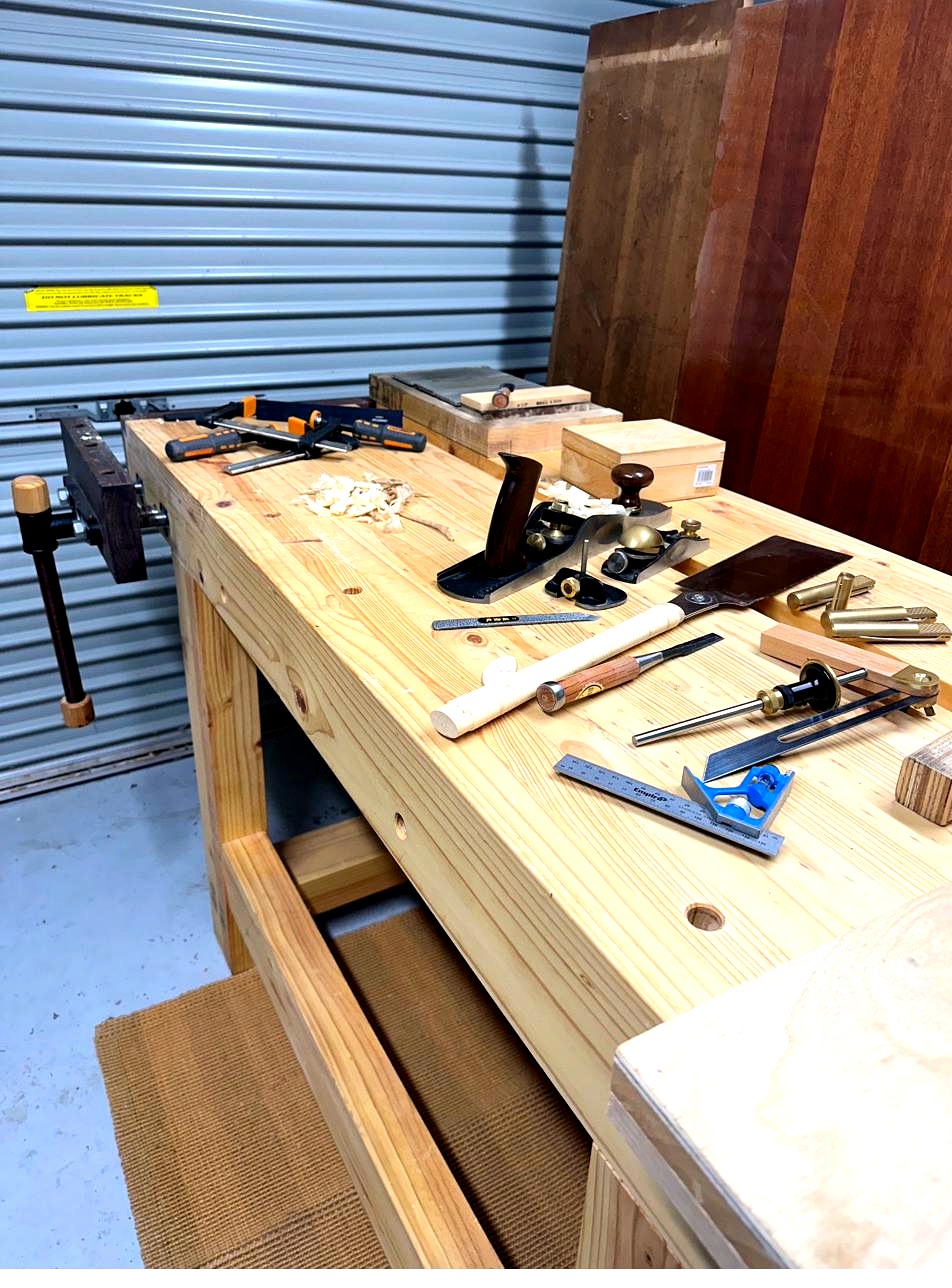 Hand tools laid out on the workbench — planes, chisels, marking gauges